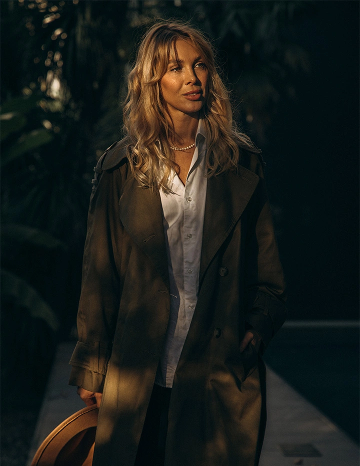 A blonde woman with her head tilted back and eyes closed, her hair flowing softly in the breeze, highlighting a smooth, contoured neck and jawline against a neutral backdrop. - Neck lift in San Francisco, CA