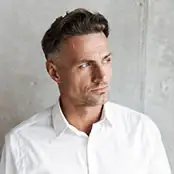 A mature man with styled dark hair and a crisp white shirt looks off-camera, displaying firm skin and a refined, youthful jawline. - Male facelift in San Francisco, CA